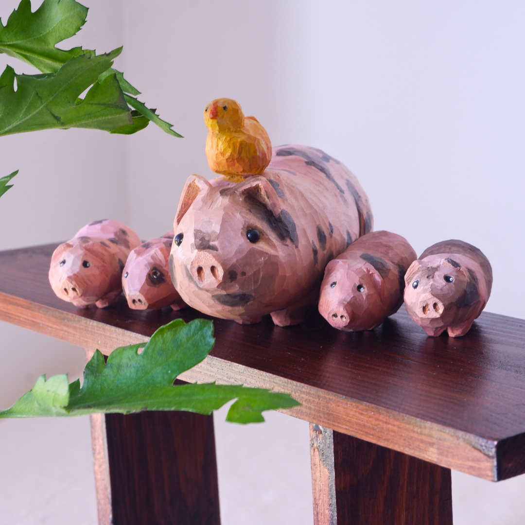 Wooden pig family figurine set by anornament - mother pig with four piglets and a yellow chick on a wooden shelf