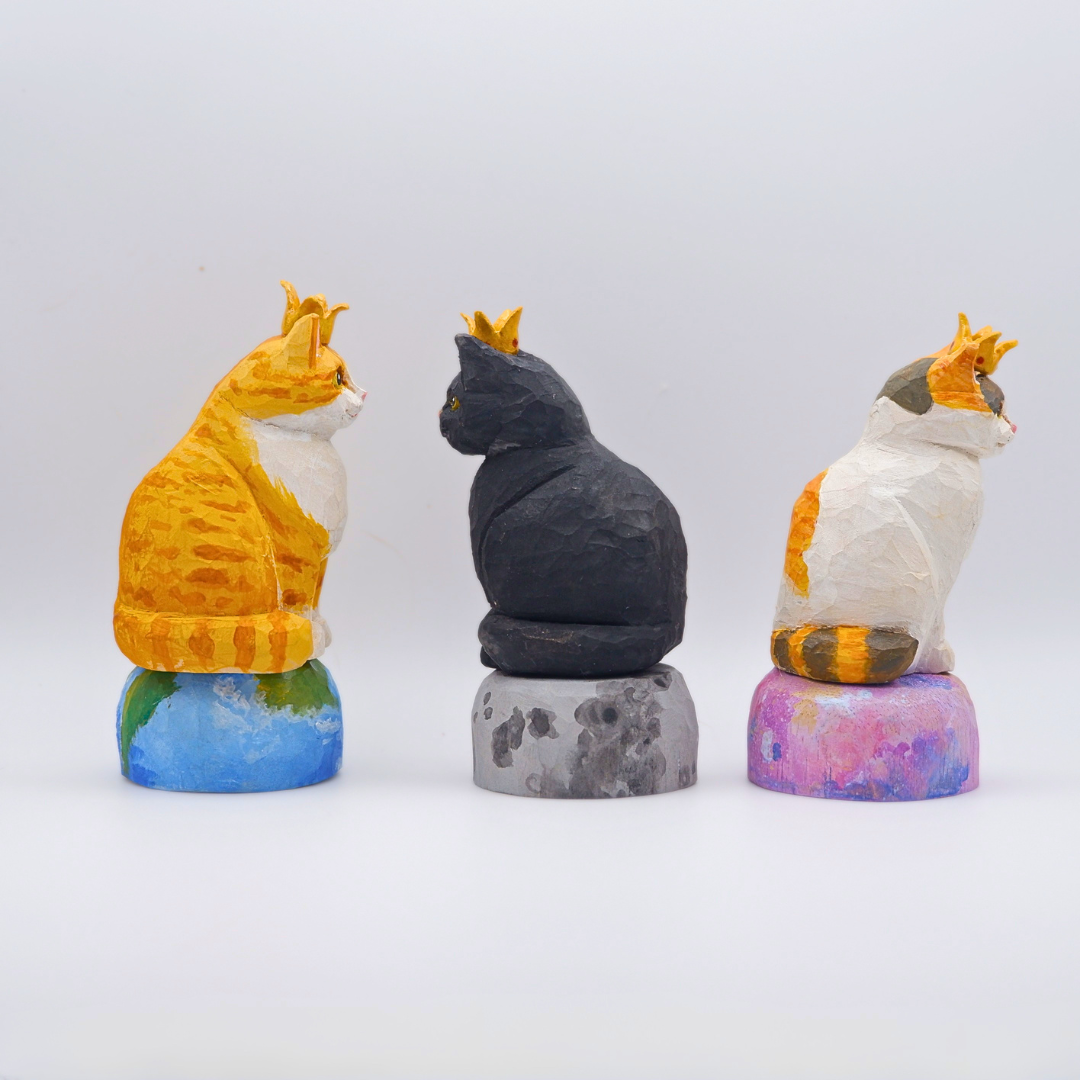 Rear view of hand-carved wooden crowned cat figurines on planet bases, anornament Universe collection